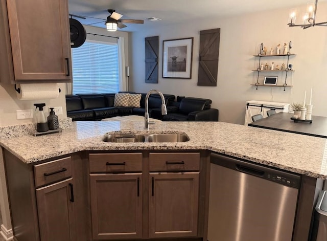 kitchen with kitchen peninsula, sink, light stone countertops, stainless steel dishwasher, and ceiling fan with notable chandelier