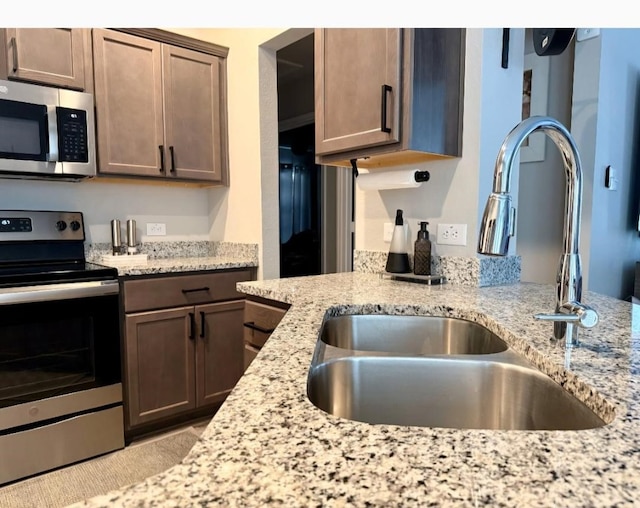 kitchen featuring sink, light stone countertops, and stainless steel appliances