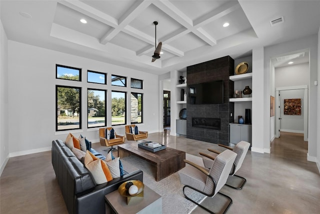 living room featuring beamed ceiling, coffered ceiling, a tiled fireplace, and built in features