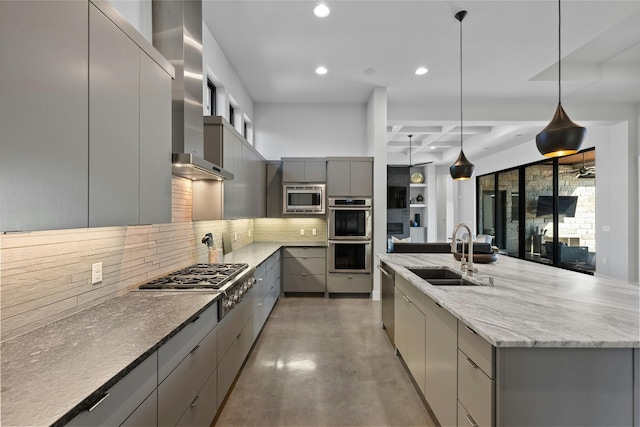 kitchen with wall chimney range hood, hanging light fixtures, stainless steel appliances, gray cabinets, and sink