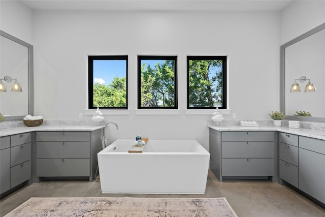 bathroom featuring vanity, a tub to relax in, and concrete floors