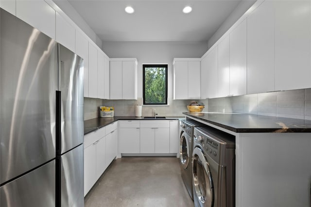 kitchen with sink, separate washer and dryer, stainless steel fridge, white cabinets, and decorative backsplash