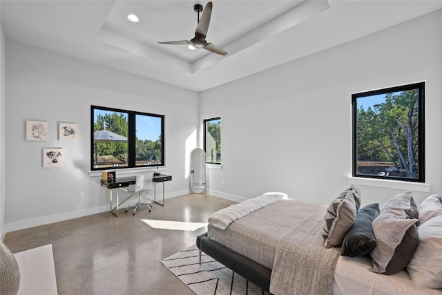 bedroom featuring a raised ceiling, concrete floors, and ceiling fan