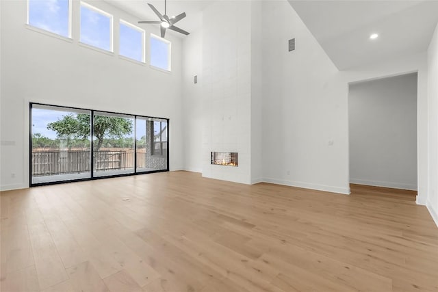 2305 Shane Ranch Dr, Cedar Park, TX 78641 - unfurnished living room featuring a high ceiling, a ceiling fan, light wood-style flooring, and a fireplace