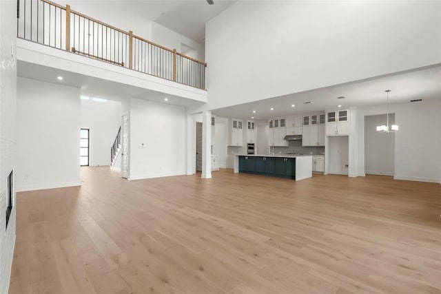 2305 Shane Ranch Dr, Cedar Park, TX 78641 - unfurnished living room with light wood-style flooring, a chandelier, stairs, and a high ceiling