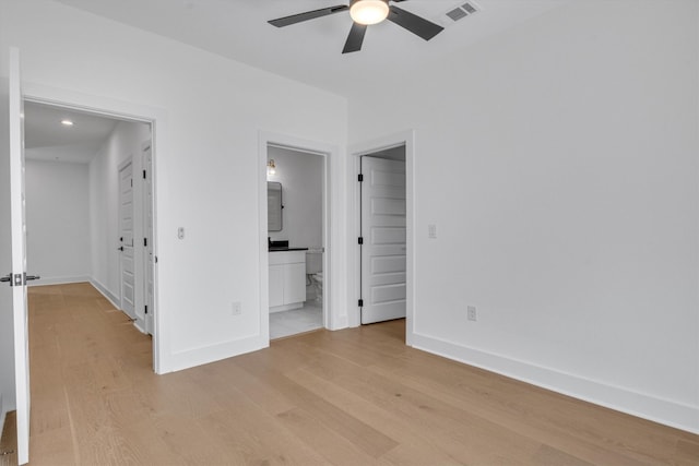 unfurnished bedroom featuring ensuite bathroom, light wood-type flooring, and ceiling fan