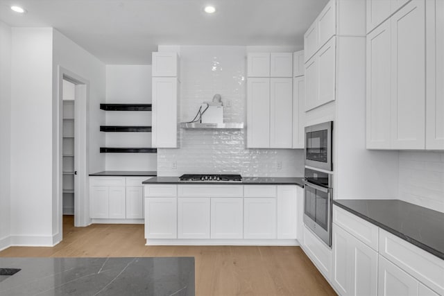 kitchen with appliances with stainless steel finishes, light wood-type flooring, and white cabinets