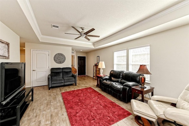 living room with light hardwood / wood-style floors, a raised ceiling, ceiling fan, and ornamental molding