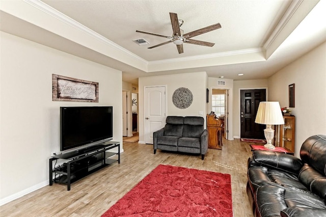 living room featuring ceiling fan, crown molding, light hardwood / wood-style flooring, and a tray ceiling