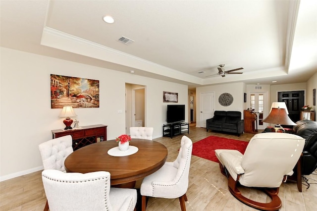 dining area featuring light wood-type flooring, a tray ceiling, ceiling fan, and ornamental molding