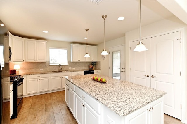 kitchen featuring sink, a center island, white cabinetry, and black appliances