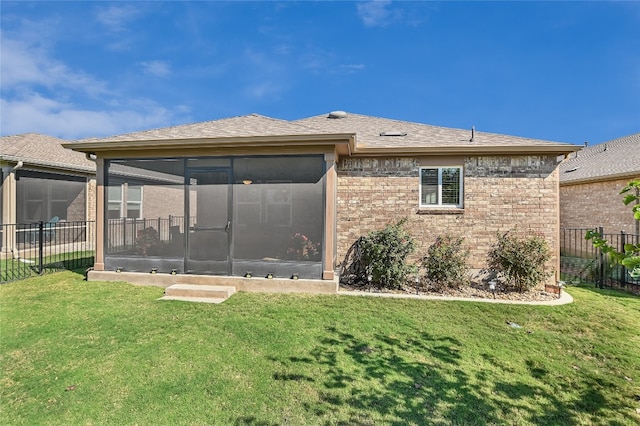 rear view of house featuring a yard and a sunroom