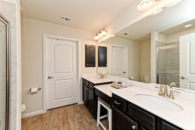 bathroom with a shower with shower door, toilet, wood-type flooring, and vanity