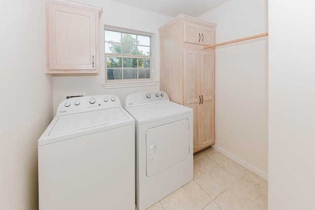 laundry room with light tile patterned floors, washing machine and dryer, and cabinets