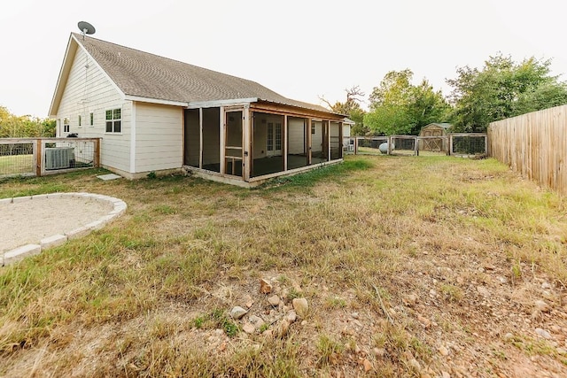 back of house featuring a sunroom, a yard, and central air condition unit