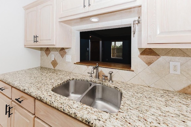 kitchen featuring light stone counters, sink, decorative backsplash, and light brown cabinets