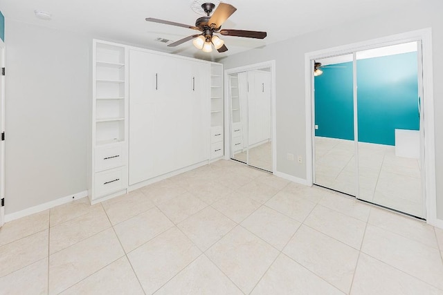 unfurnished bedroom featuring light tile patterned floors, two closets, and ceiling fan