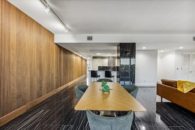 dining space with wooden walls and track lighting