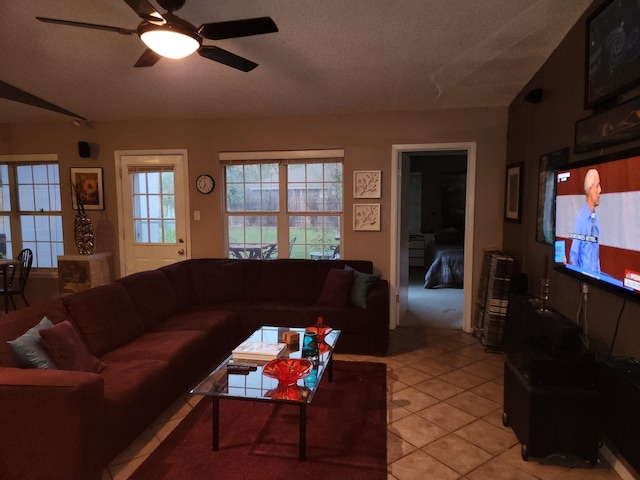 living room featuring light tile patterned flooring, ceiling fan, and a textured ceiling