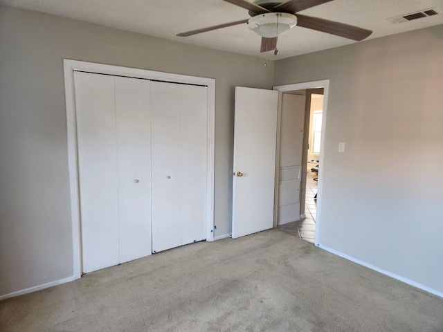 unfurnished bedroom featuring light carpet, a closet, and ceiling fan