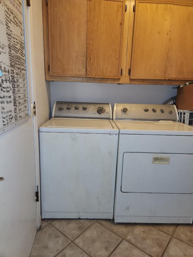 laundry area featuring cabinets, light tile patterned floors, and washer and clothes dryer