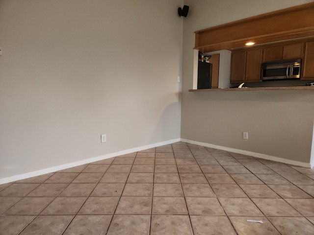 kitchen featuring light tile patterned flooring and black refrigerator