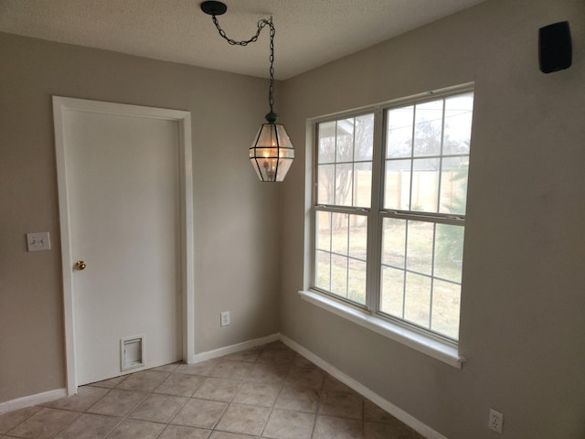 unfurnished dining area featuring a textured ceiling and light tile patterned floors