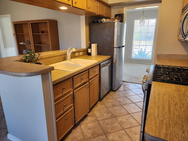 kitchen featuring pendant lighting, sink, stainless steel appliances, and kitchen peninsula