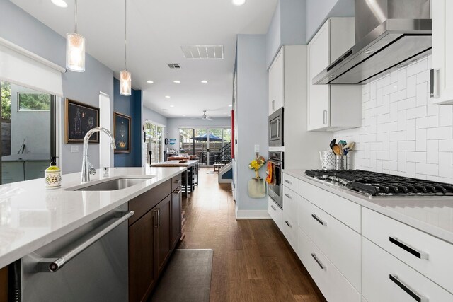 kitchen with a sink, visible vents, recessed lighting, wall chimney range hood, and appliances with stainless steel finishes