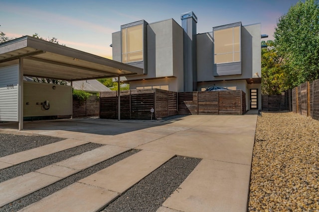 view of front of house with stucco siding, driveway, and fence