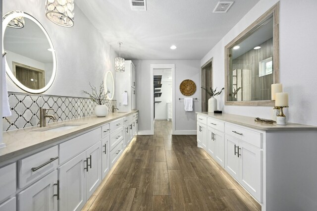 bathroom featuring tasteful backsplash, an inviting chandelier, hardwood / wood-style flooring, walk in shower, and vanity