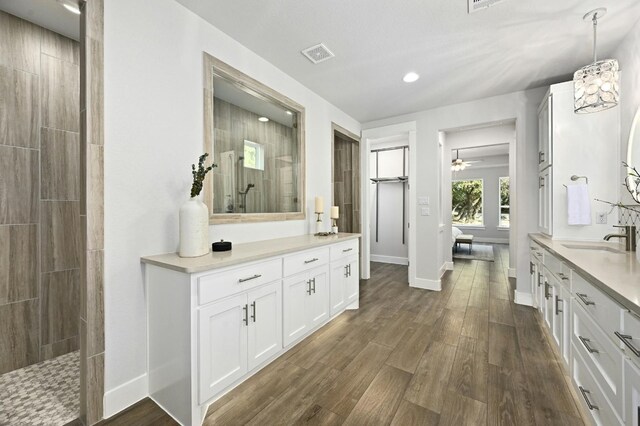 bathroom featuring vanity, a tile shower, wood-type flooring, and a chandelier