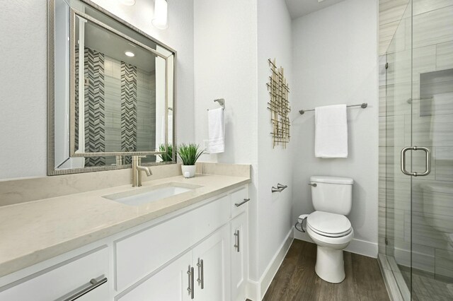 bathroom with vanity, hardwood / wood-style floors, toilet, and an enclosed shower