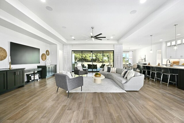 living room featuring ceiling fan, sink, and light wood-type flooring