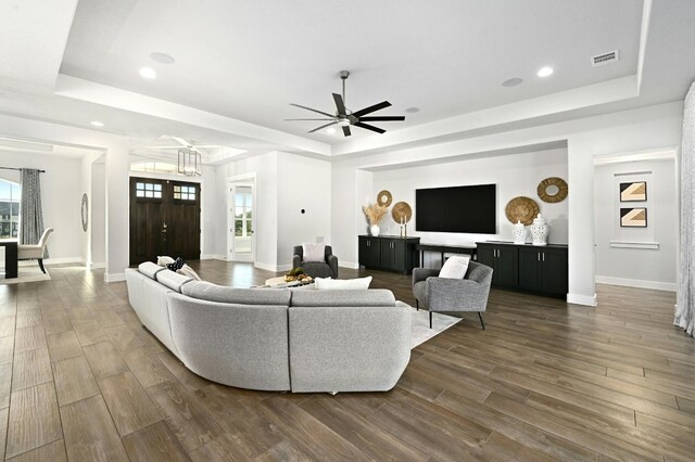 living room featuring dark hardwood / wood-style floors, a tray ceiling, and a wealth of natural light