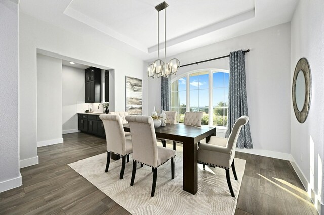 dining space featuring a notable chandelier, dark hardwood / wood-style floors, sink, and a tray ceiling