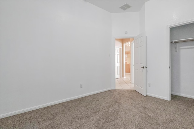 unfurnished bedroom featuring light carpet and a closet