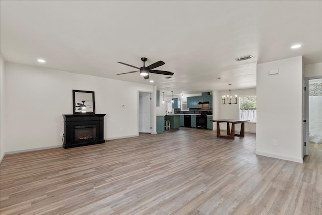 unfurnished living room featuring light wood-type flooring and ceiling fan with notable chandelier