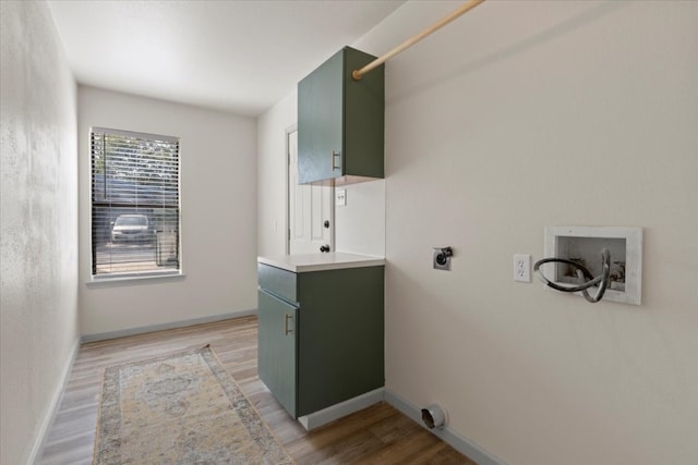 washroom with hookup for a washing machine, light hardwood / wood-style flooring, electric dryer hookup, and cabinets