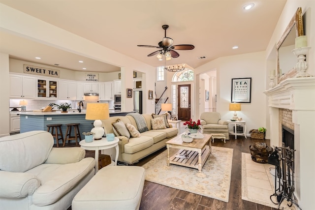 living room with dark hardwood / wood-style floors, ceiling fan, sink, and a fireplace