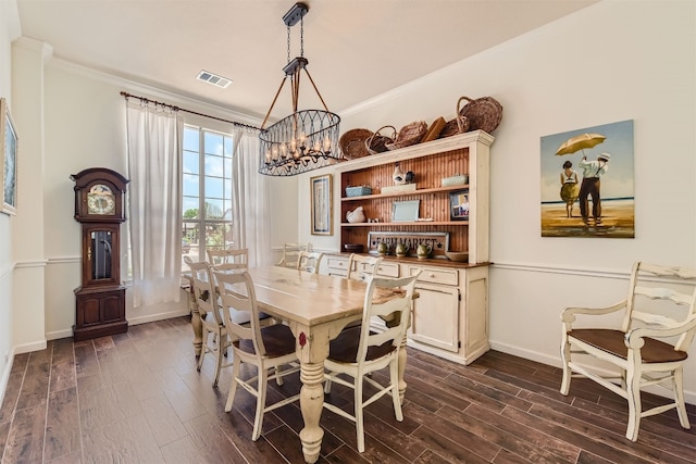 dining space with crown molding, dark wood-type flooring, and a notable chandelier