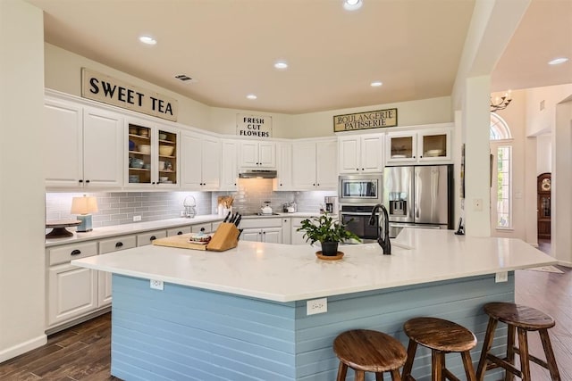 134 Fairwood Dr, Georgetown, TX 78628 - kitchen with stainless steel appliances, dark wood-style flooring, tasteful backsplash, a breakfast bar area, and white cabinets