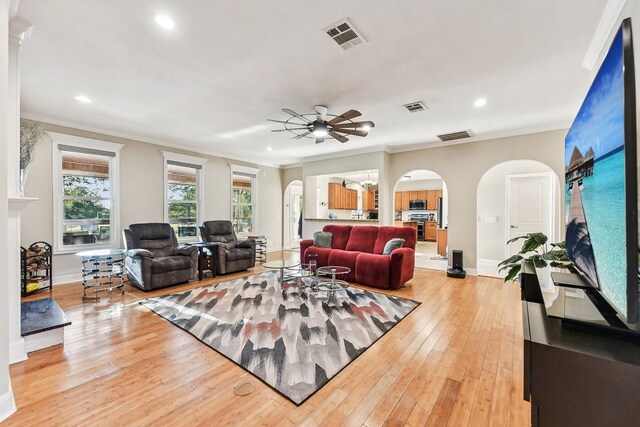 living room with ornamental molding, light wood-type flooring, and ceiling fan