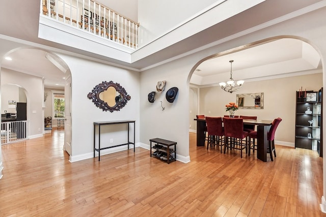 dining room featuring an inviting chandelier, crown molding, a tray ceiling, and light hardwood / wood-style floors