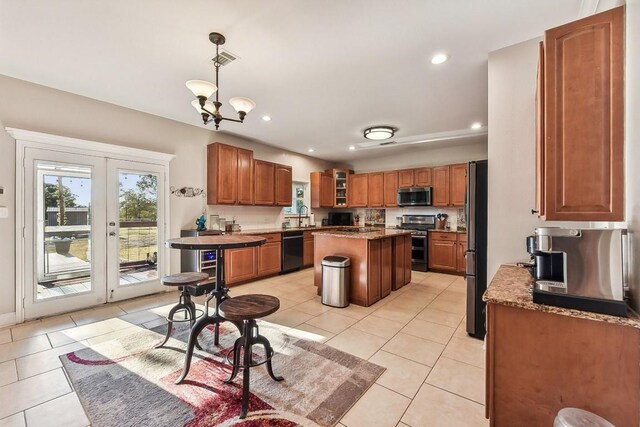 kitchen featuring black appliances, a kitchen island, pendant lighting, light tile patterned floors, and a chandelier