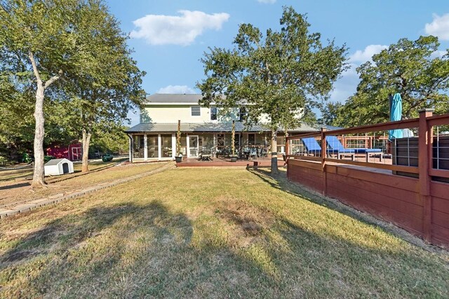 view of yard featuring a storage shed, a wooden deck, and a sunroom