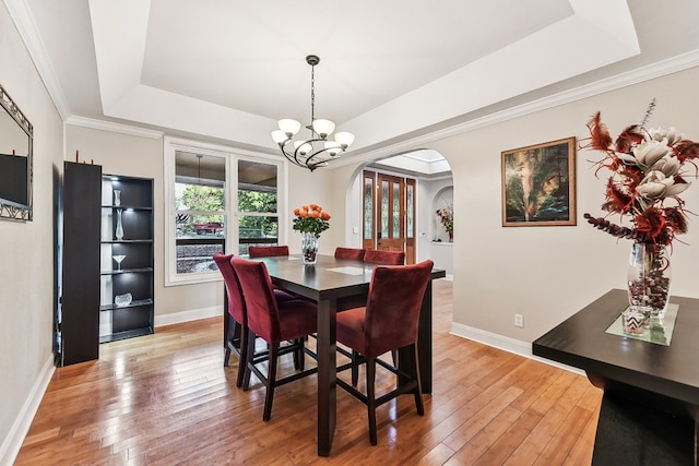 dining area with ornamental molding, hardwood / wood-style flooring, and a raised ceiling