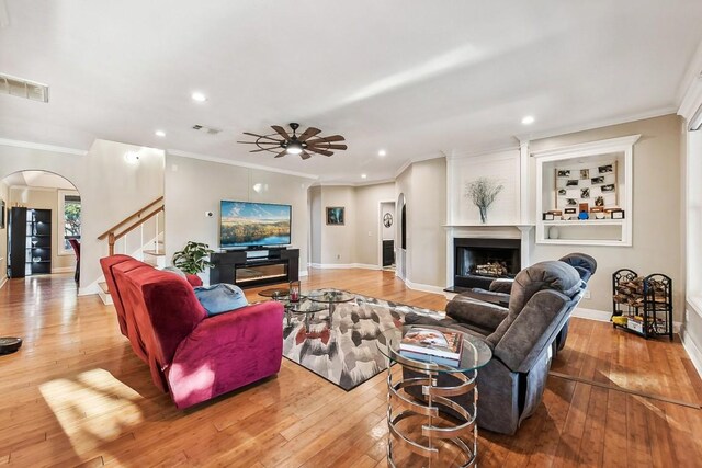 living room featuring light hardwood / wood-style flooring, ceiling fan, and crown molding