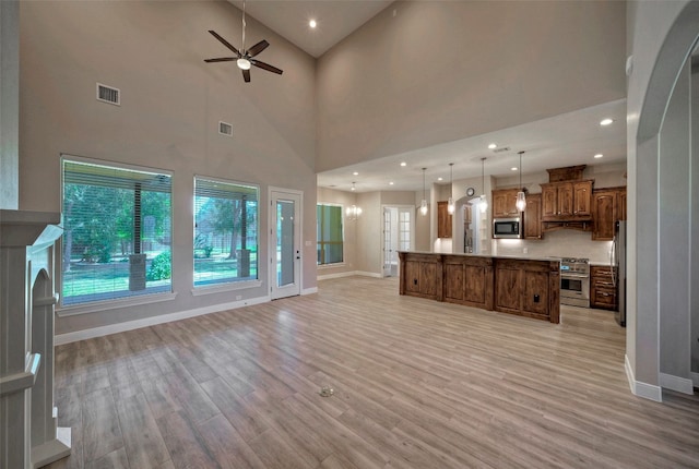 unfurnished living room featuring light hardwood / wood-style floors, high vaulted ceiling, and ceiling fan with notable chandelier