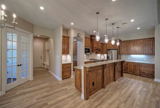 kitchen featuring french doors, stainless steel appliances, and a center island with sink